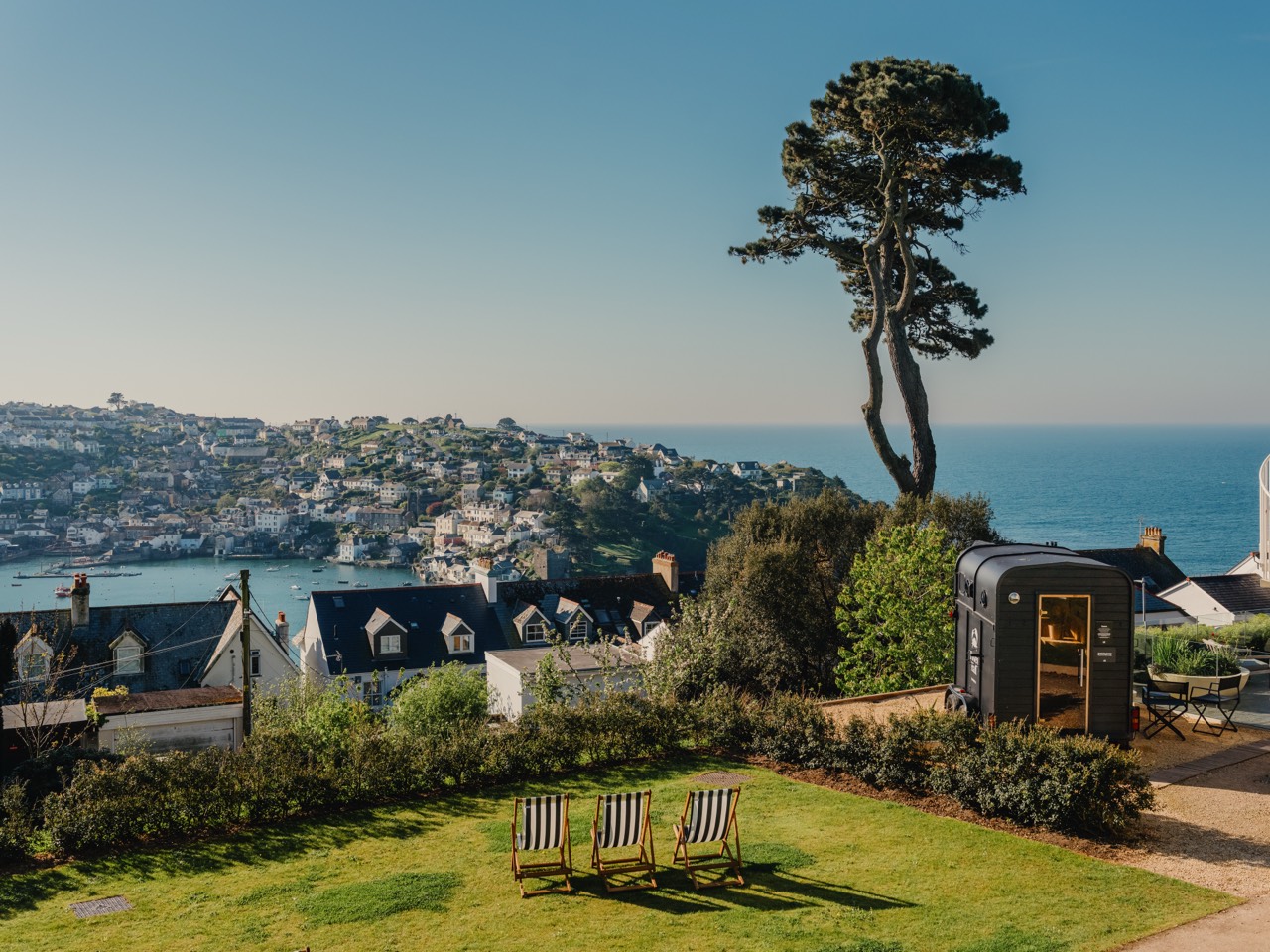 The horsebox sauna in the gardens of Fowey Hall Hotel with deckchairs and a panoramic view over the Fowey estuary