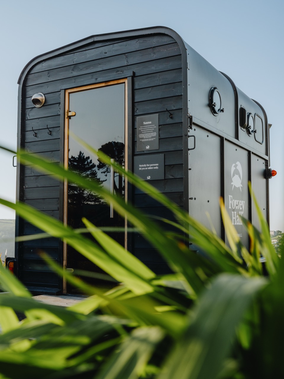 The Fowey Hall horsebox sauna exterior with its door open at dusk