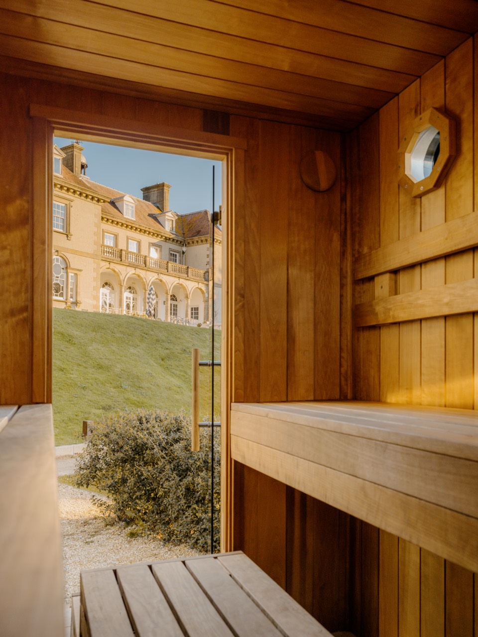 Inside the Sauna Box sauna looking out through the open door to the grand Fowey Hall Hotel facade