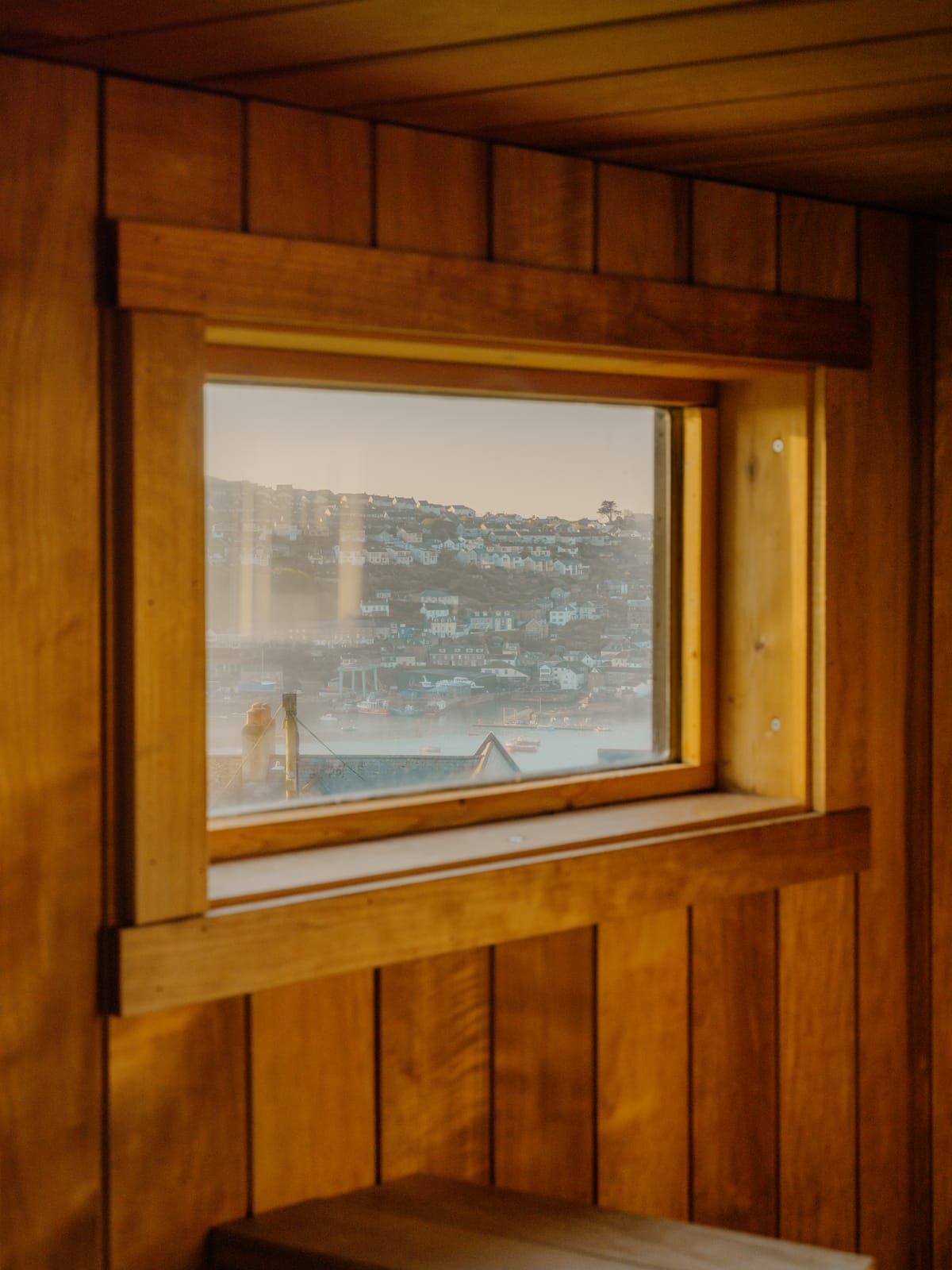 The sauna window framing a misty view over Fowey harbour from the bench