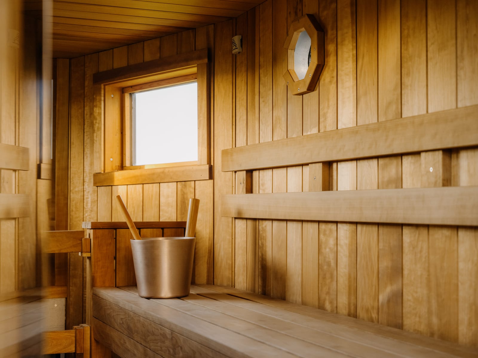 Bucket and ladle on the sauna bench in warm afternoon light