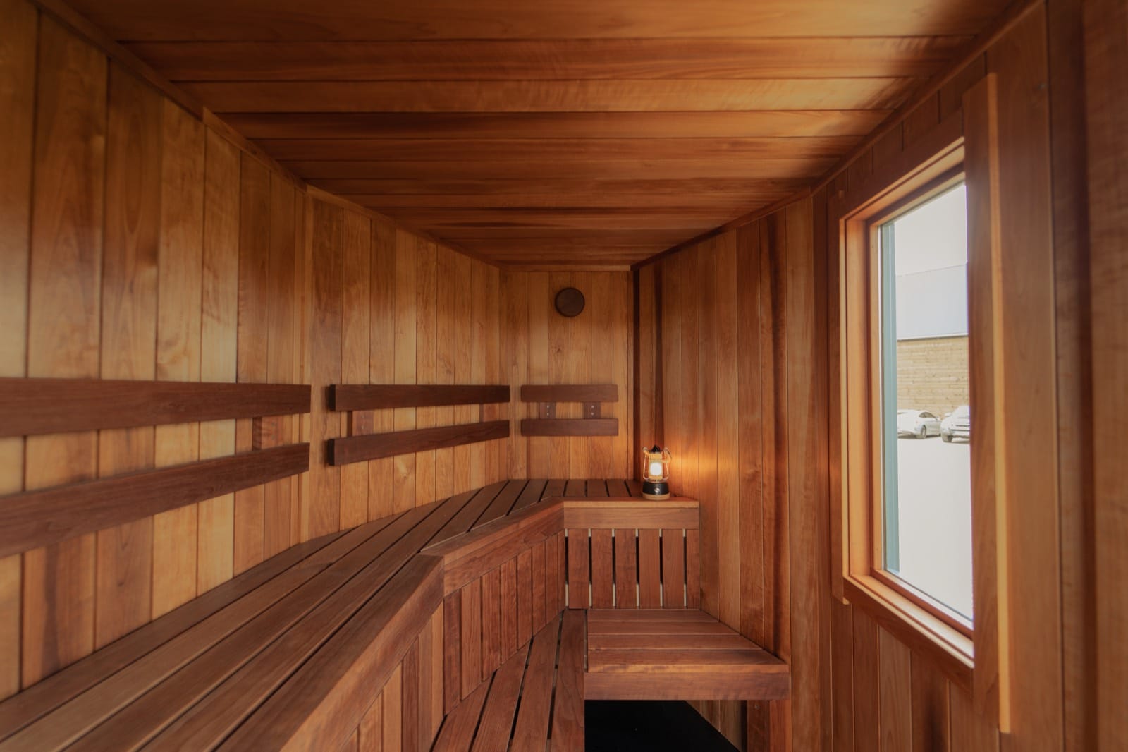Looking down the cedar-lined interior of Island Sauna Shack towards the wood-fired stove and open door onto open farmland