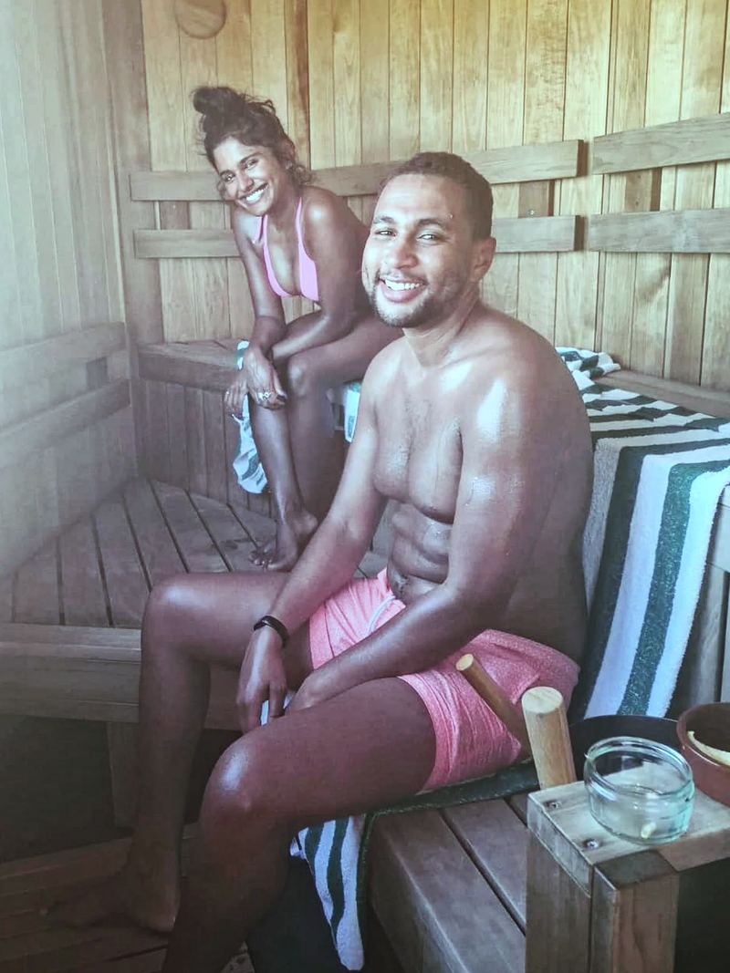 A woman and a man smiling on the benches inside a Sauna Box sauna