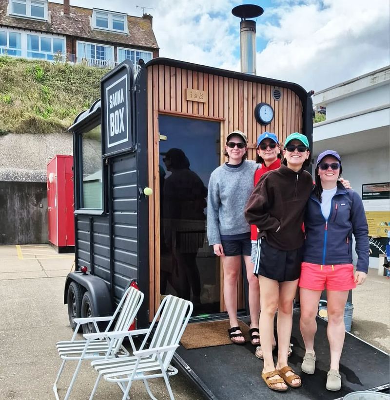 Four friends in caps beside the Sheringham horsebox sauna