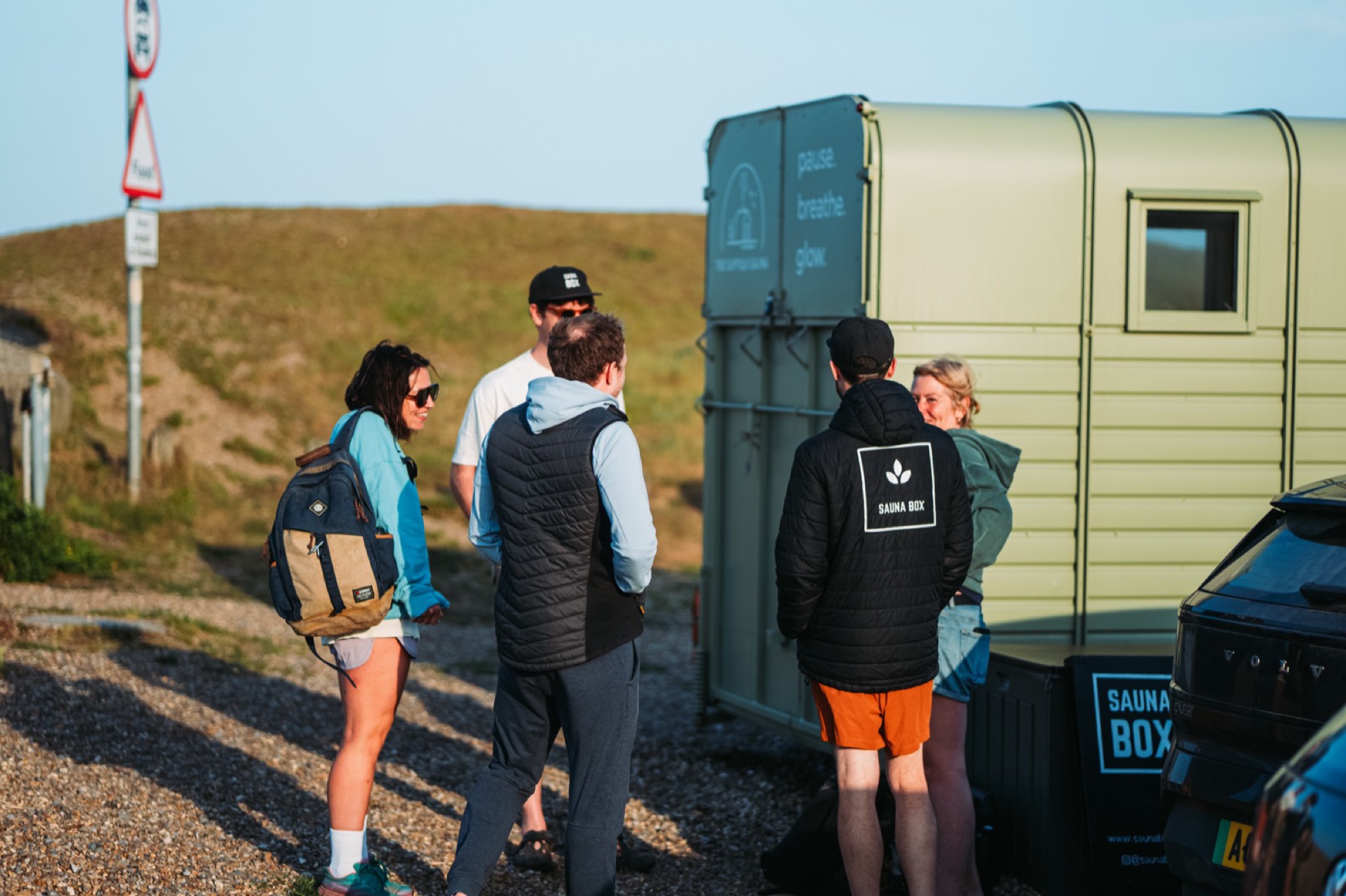 A group gathered around a Sauna Box horsebox sauna at a festival
