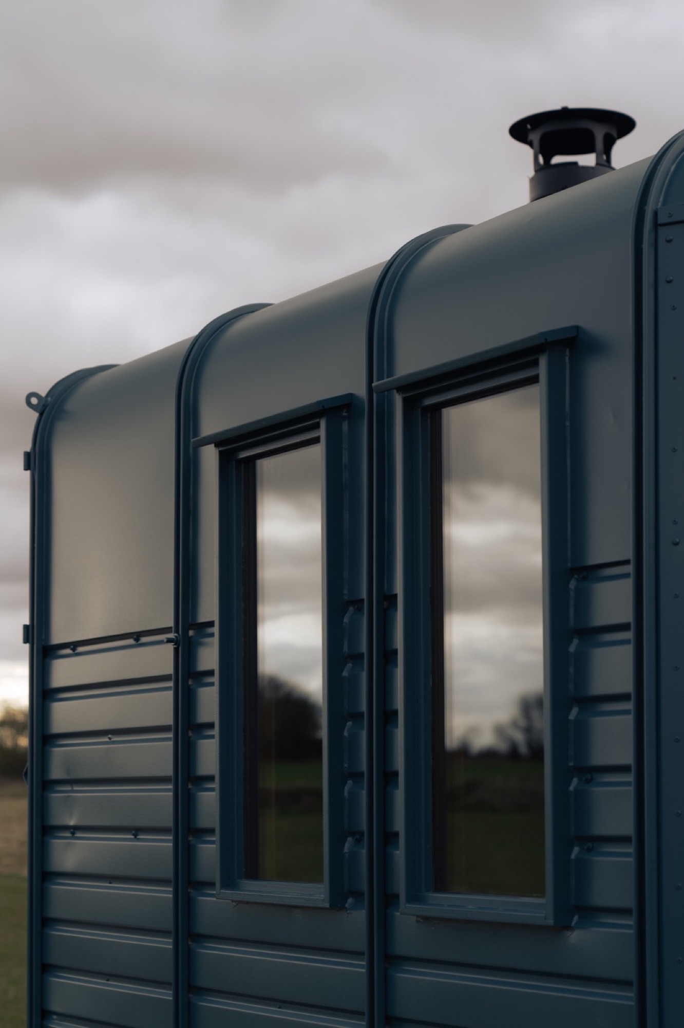 A handcrafted horsebox sauna with panoramic windows and cast-iron chimney detail