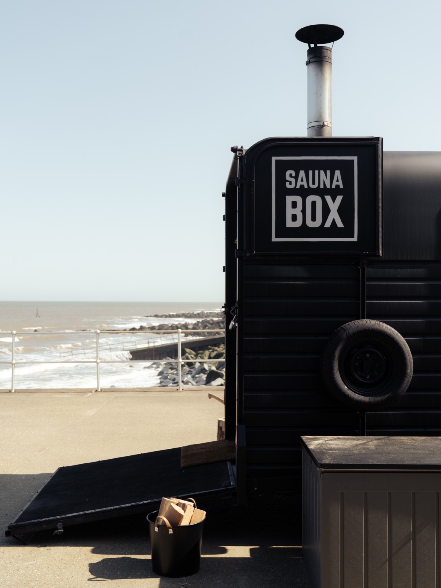 A Sauna Box horsebox sauna positioned on a sandy beach overlooking the sea