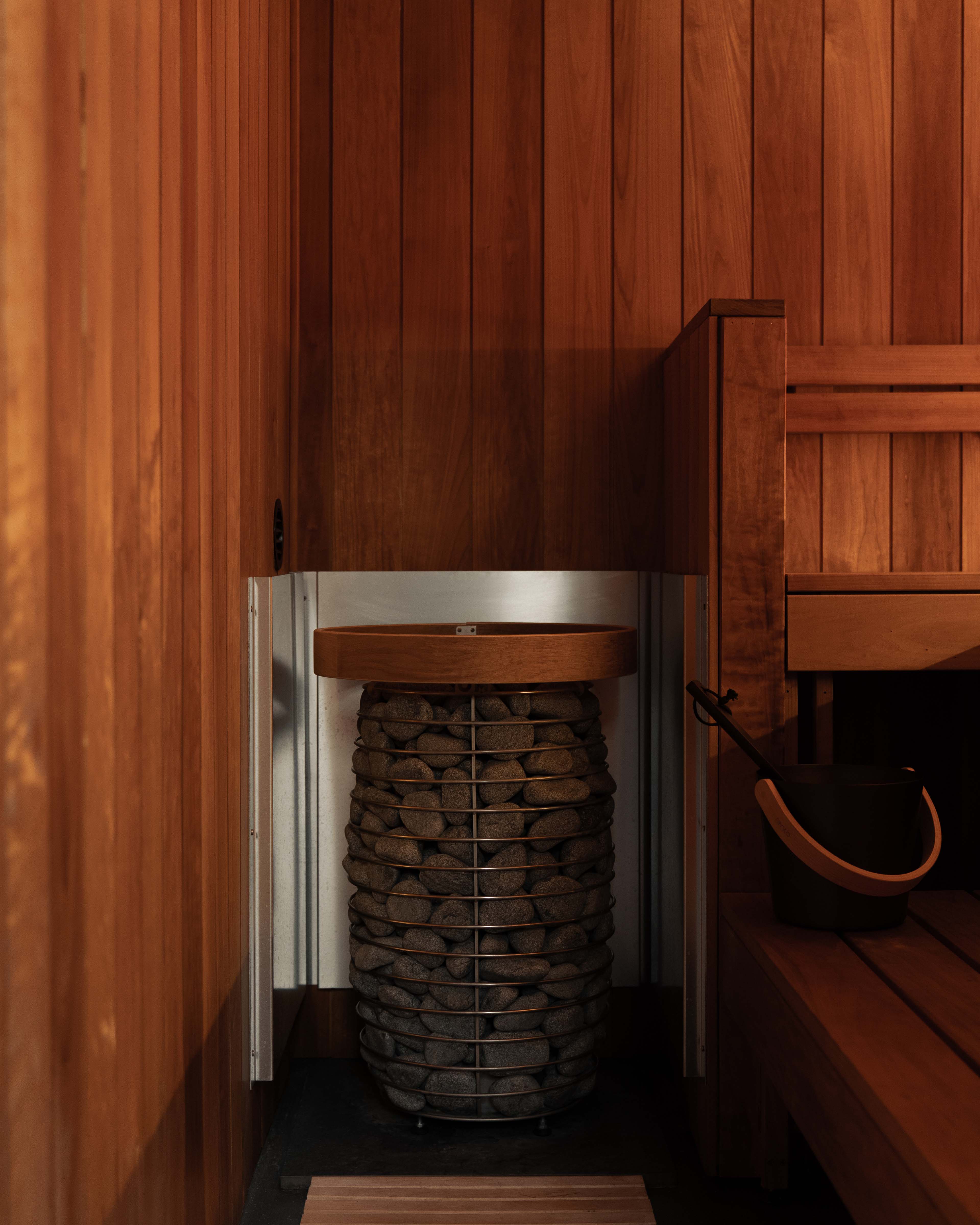 Electric sauna heater loaded with stones, timber surround