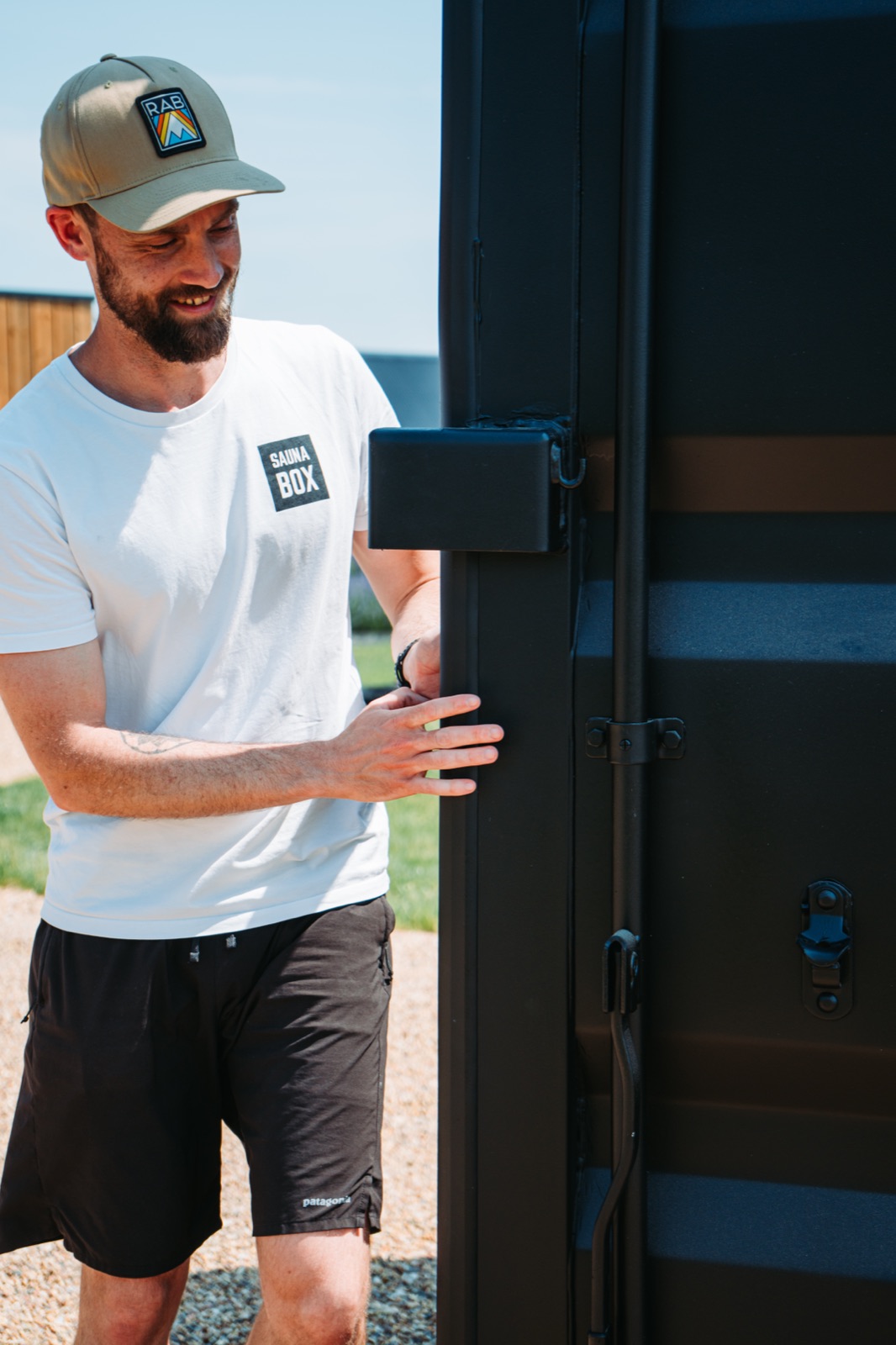 A man opening the door of a black Sauna Box container sauna